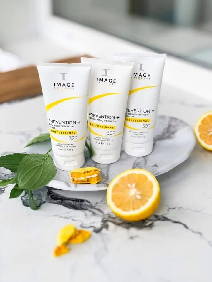 Three skincare tubes arranged on a marble surface with lemon halves and green leaves
